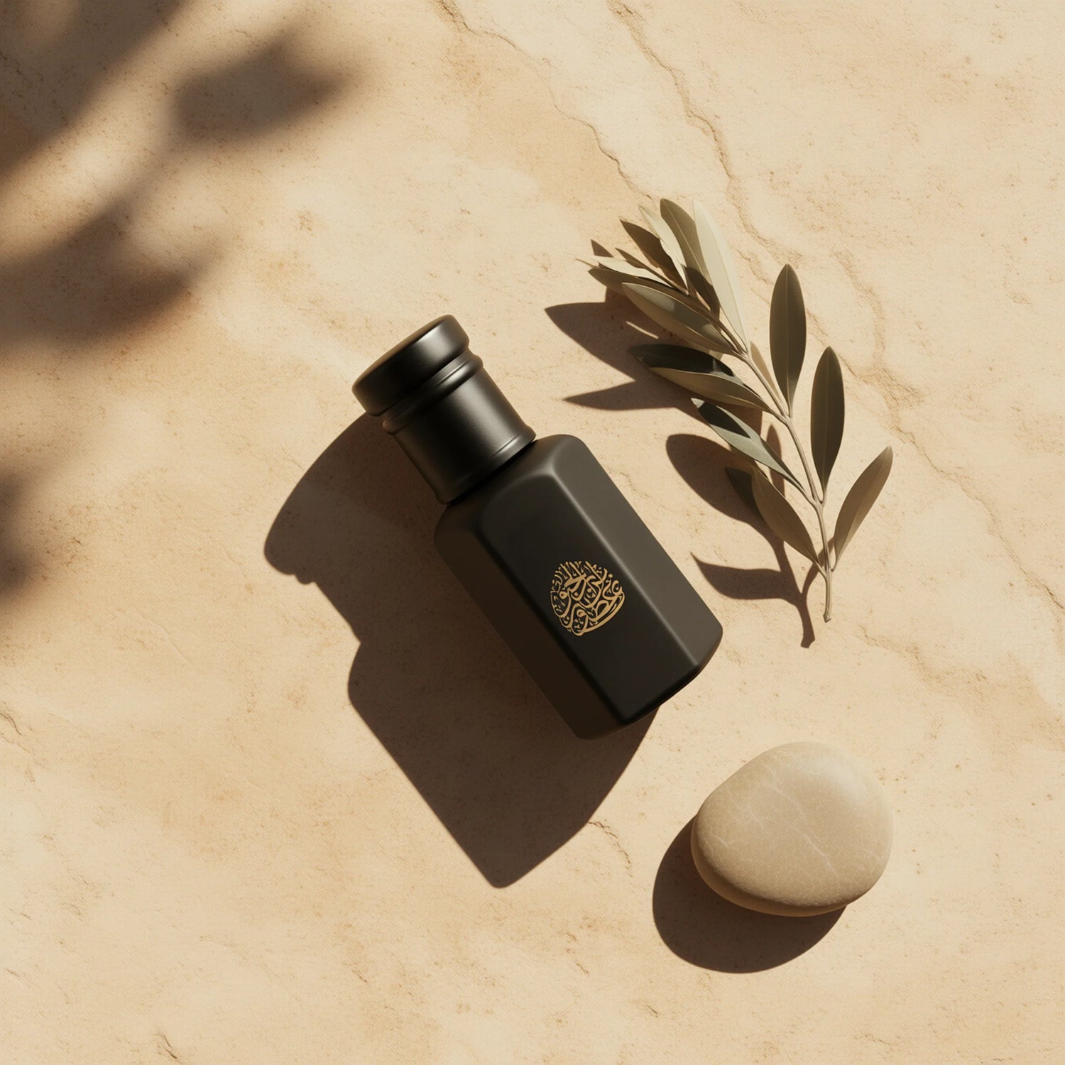 Matte black fragrance bottle with gold detailing, placed on a textured stone surface with an olive branch.