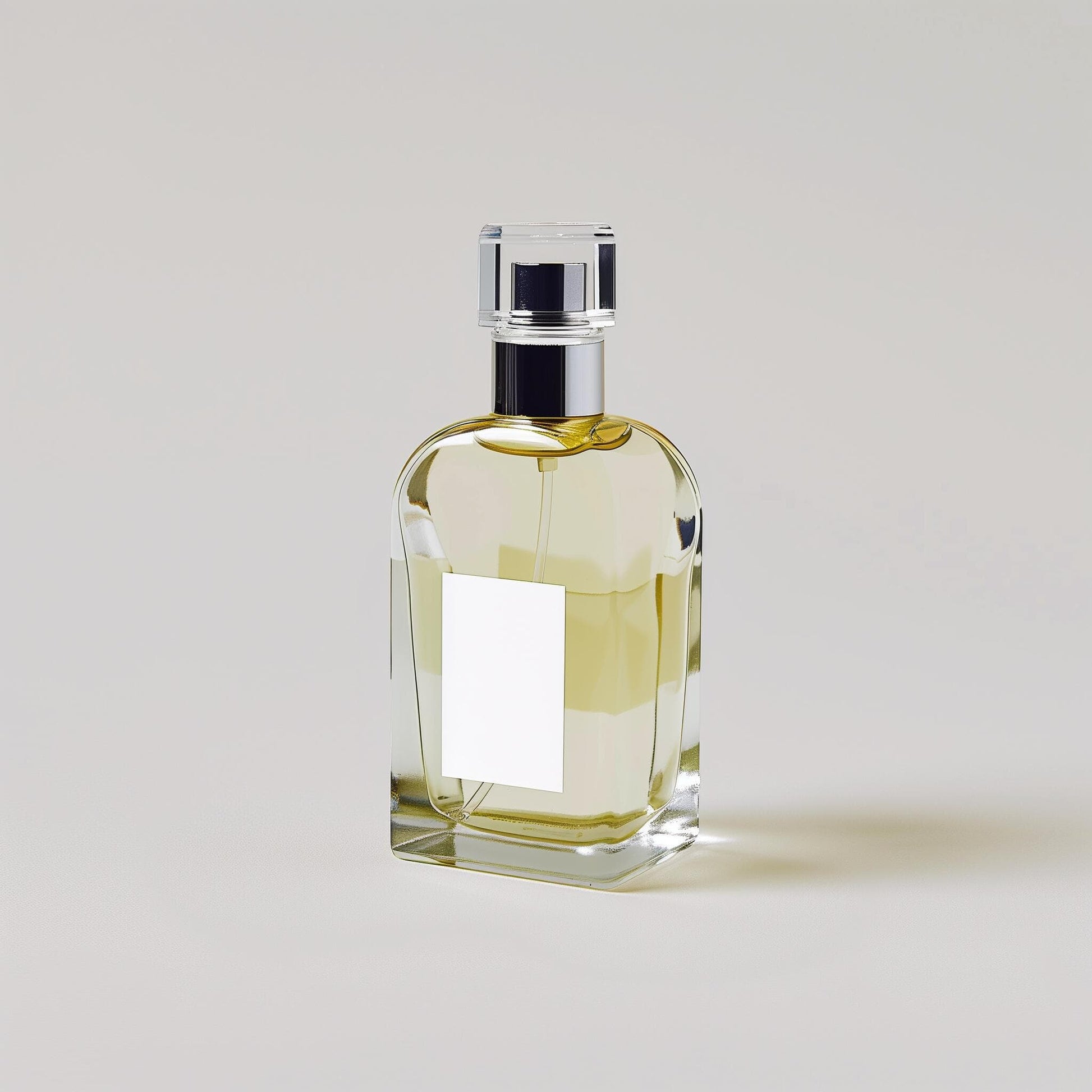 Clear glass perfume bottle with a rectangular label and golden liquid, by Ibn Al Jebouri Perfumes.